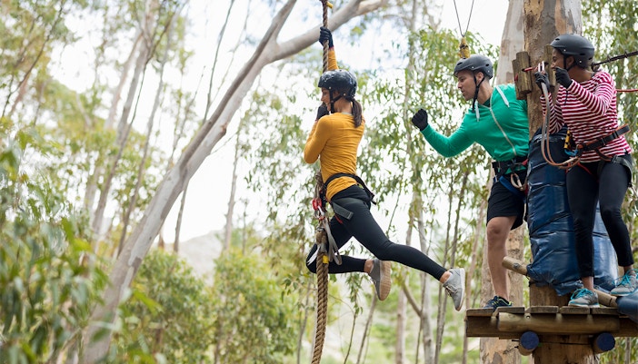 Person ziplining at ESCAPE Penang Aerobat, Malaysia, surrounded by lush greenery.