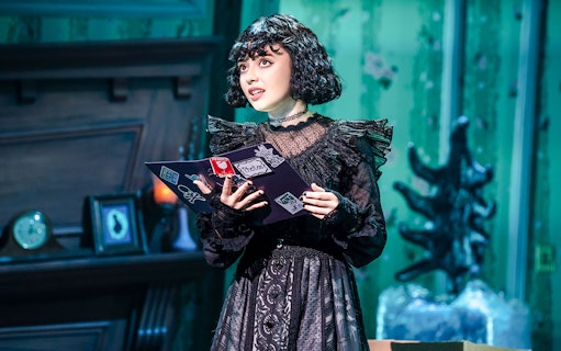 Performer on stage at Beetlejuice Broadway show holding a book.