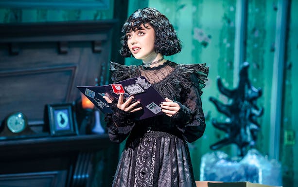 Performer on stage at Beetlejuice Broadway show holding a book.