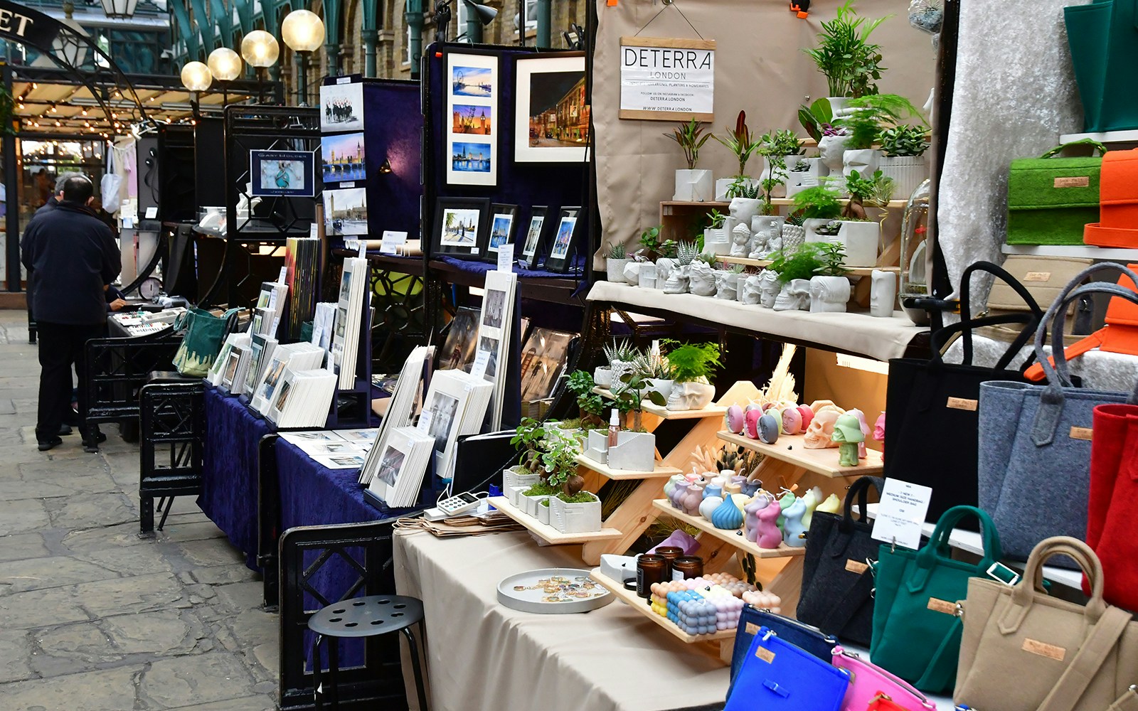 Market stalls with art, plants, and bags in Covent Garden district, London.
