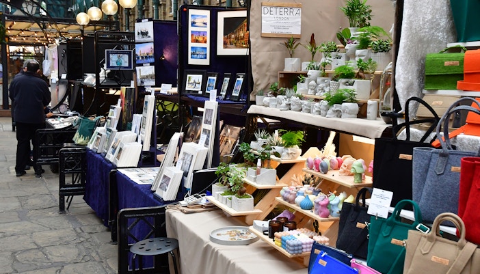 Market stalls with art, plants, and bags in Covent Garden district, London.