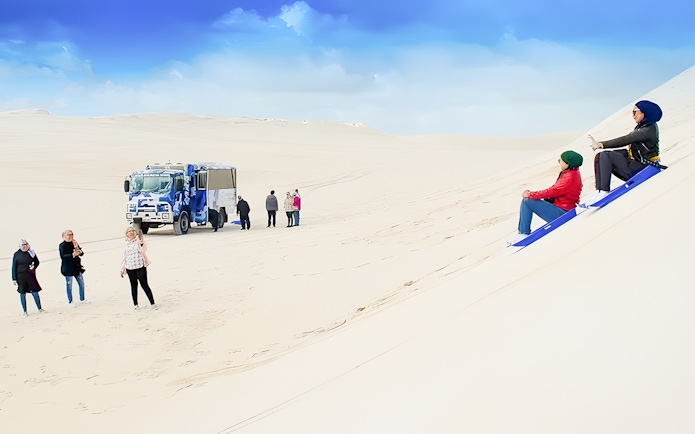 People sandboarding on dunes with a 4WD vehicle in Lancelin, Australia.