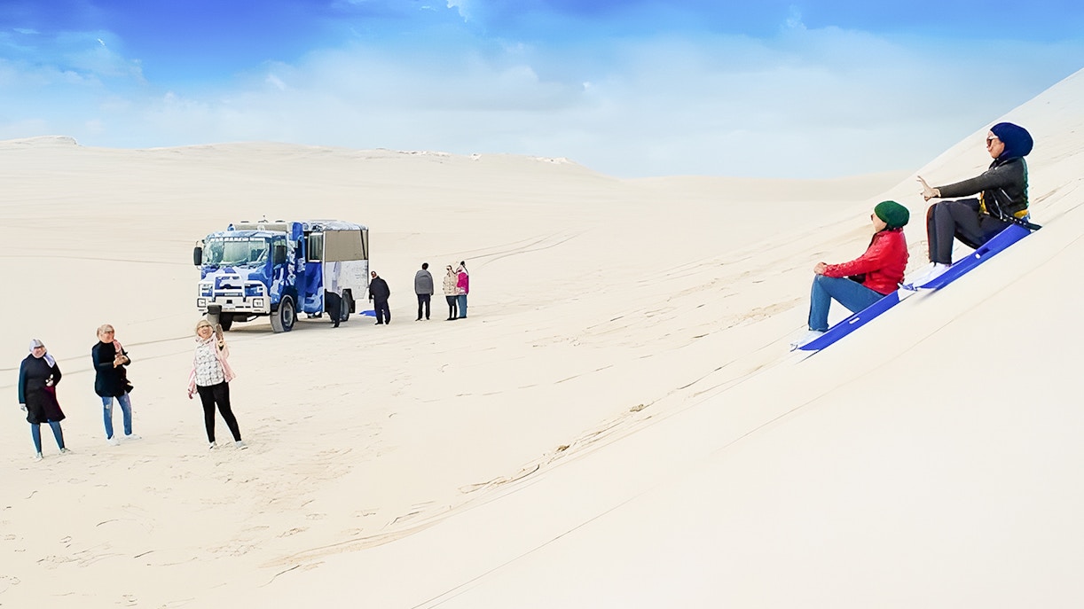 People sandboarding on dunes with a 4WD vehicle in Lancelin, Australia.