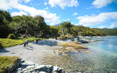 Visitors walking along the shoreline in Tierra del Fuego National Park, Argentina.