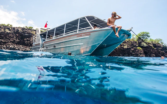 Catamaran anchored at Kealakekua Bay with snorkelers in the water.