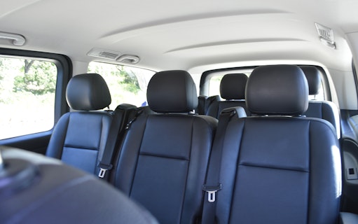 Interior of a private transfer vehicle at Athens Airport with black leather seats.