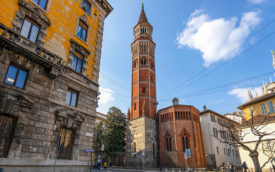 Church of St Gottardo's red brick tower in Milan with surrounding buildings.