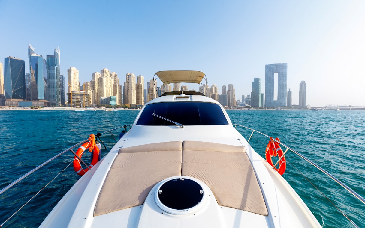 Private yacht cruising with Dubai skyline in the background.
