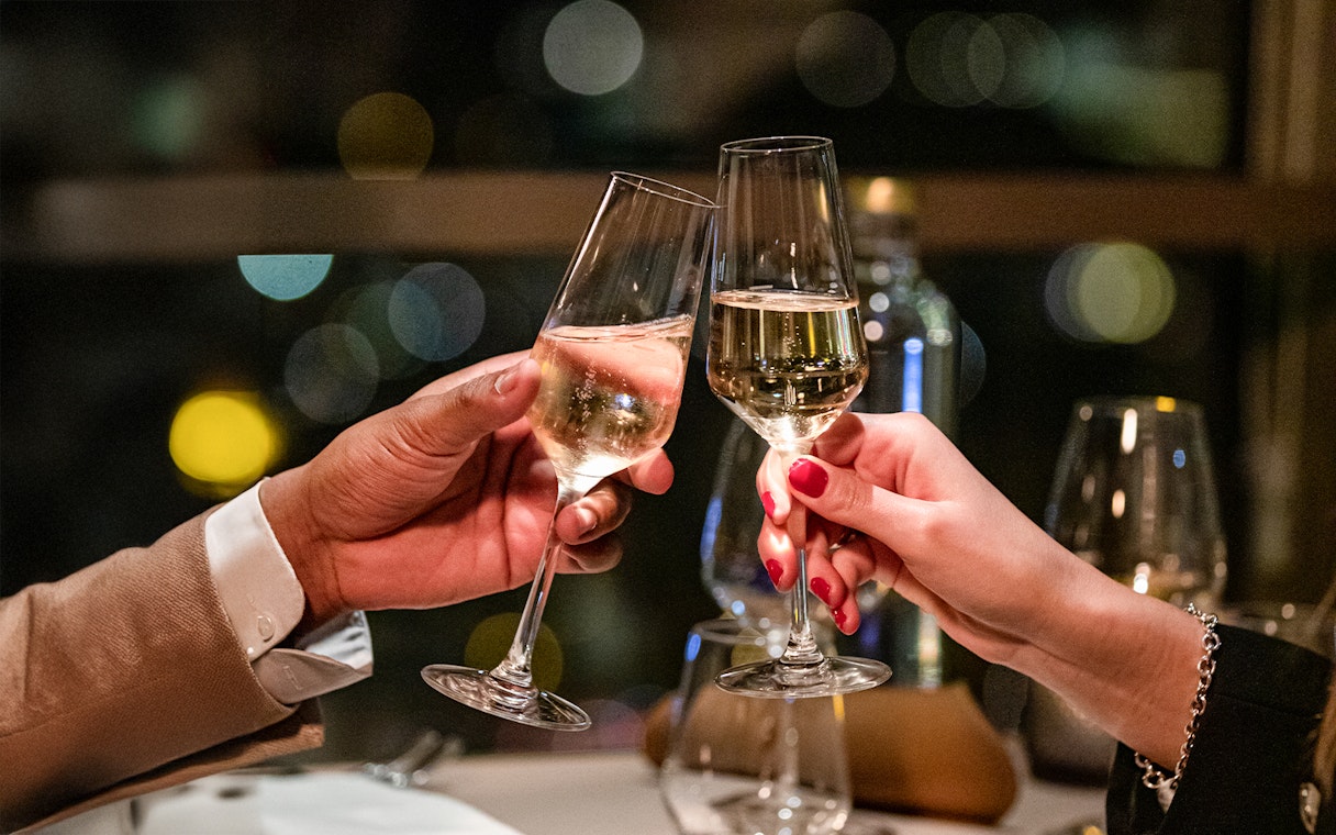 Toasting champagne glasses in a dimly lit restaurant setting.