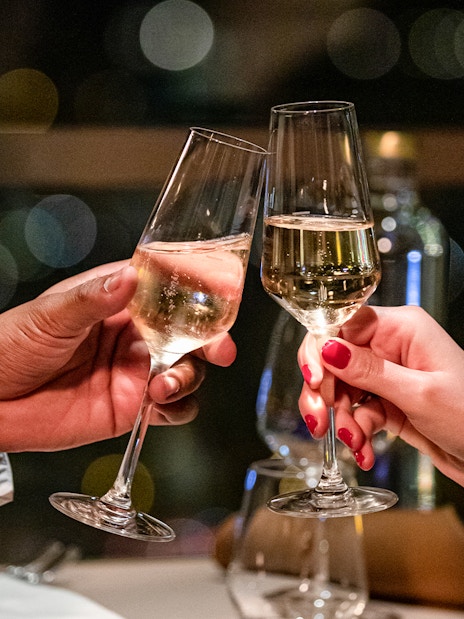 Toasting champagne glasses in a dimly lit restaurant setting.