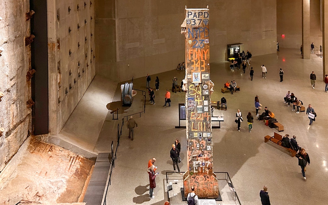 Final column at 9/11 Museum in New York City with visitors exploring exhibits.