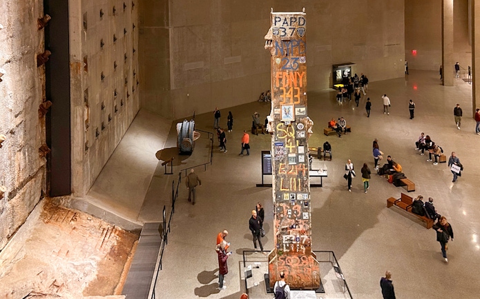 Final column at 9/11 Museum in New York City with visitors exploring exhibits.