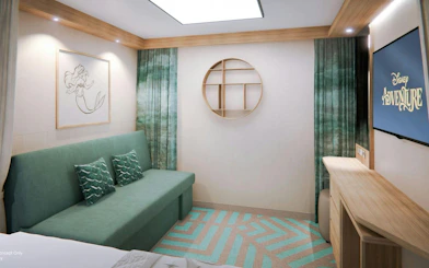 Deluxe cruise cabin with sofa, mermaid artwork, and TV displaying "Adventure.