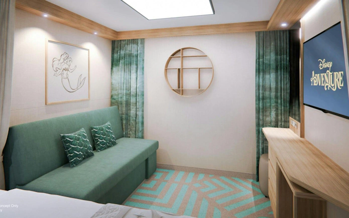 Deluxe cruise cabin with sofa, mermaid artwork, and TV displaying "Adventure.