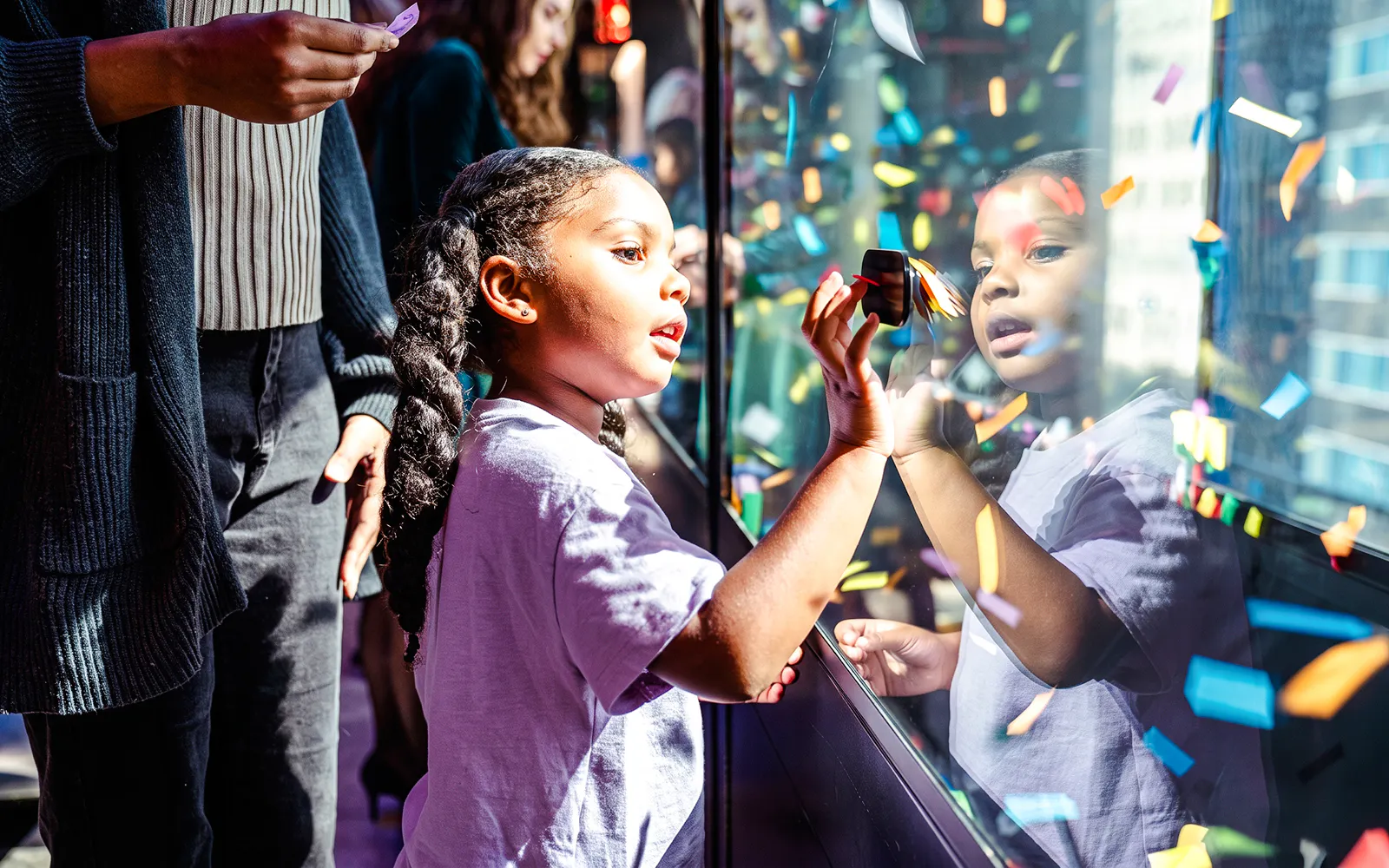 Child interacting with confetti display at One Times Square, New York City.