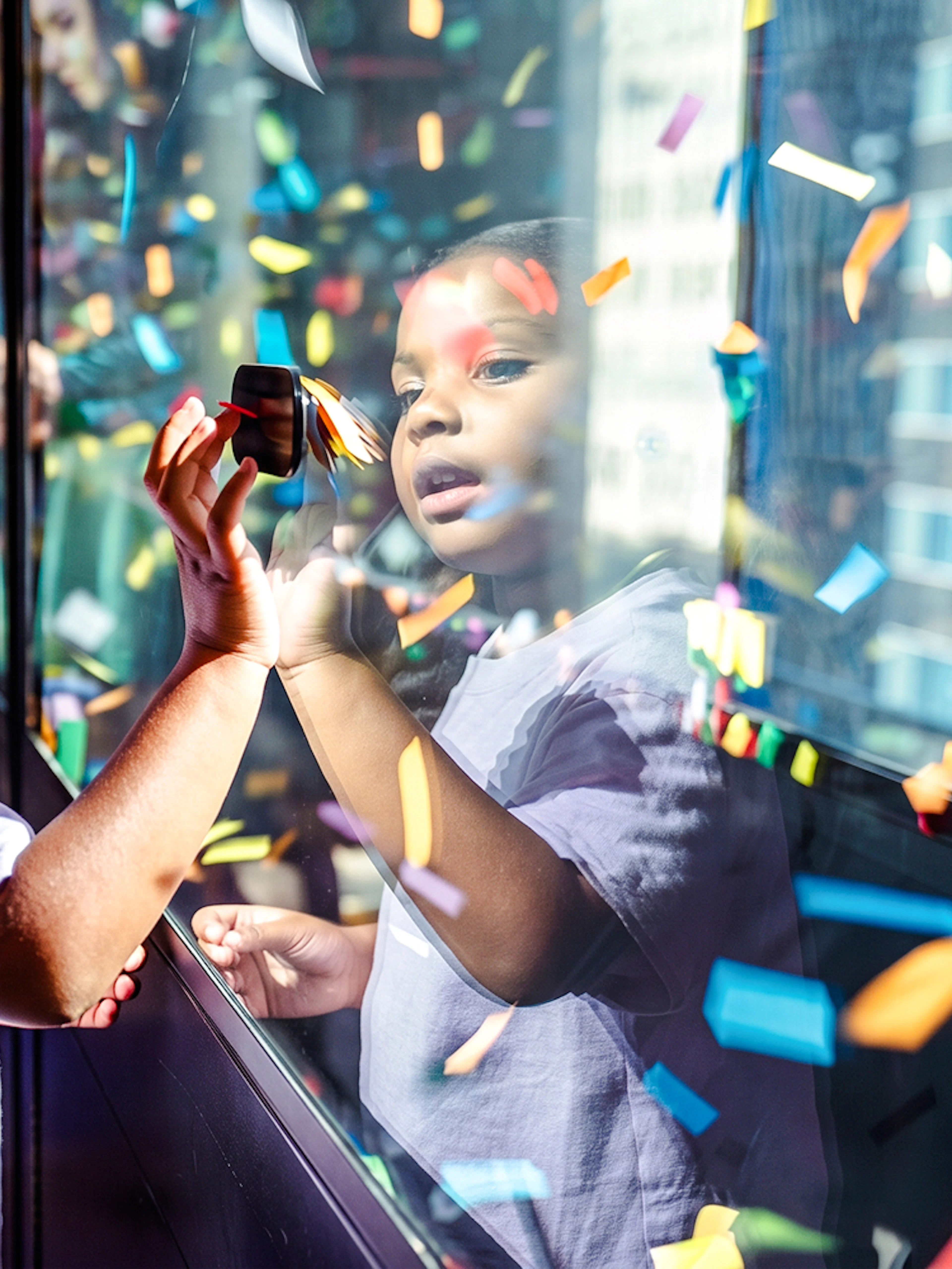 Child interacting with confetti display at One Times Square, New York City.