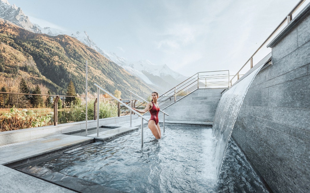 Visitor enjoying thermal bath at QC Terme Chamonix with mountain view.
