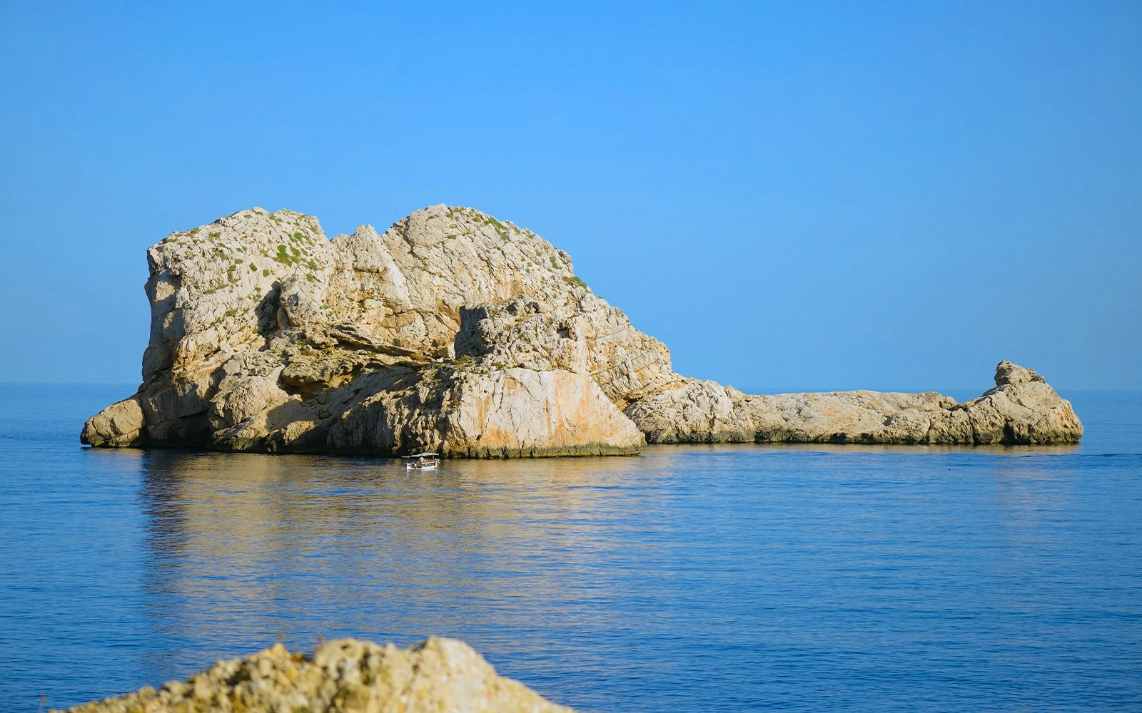 Islote Ses Margalides rock formation in clear blue sea.