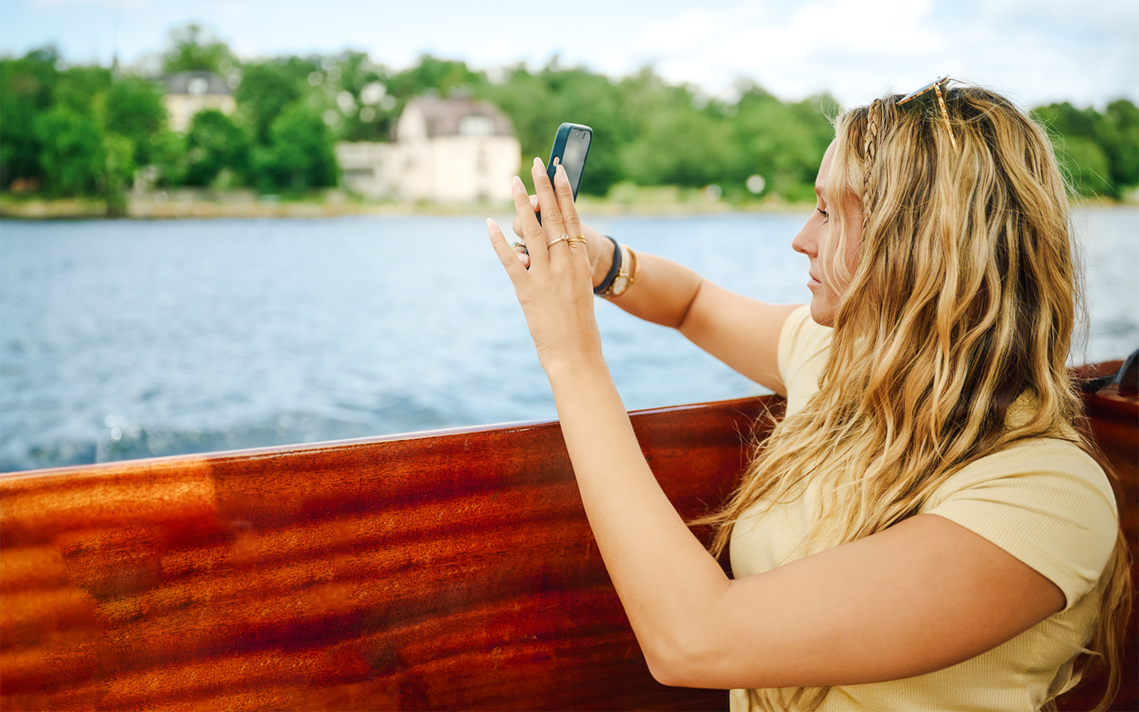 Woman taking photo on wooden boat in Stockholm Archipelago.