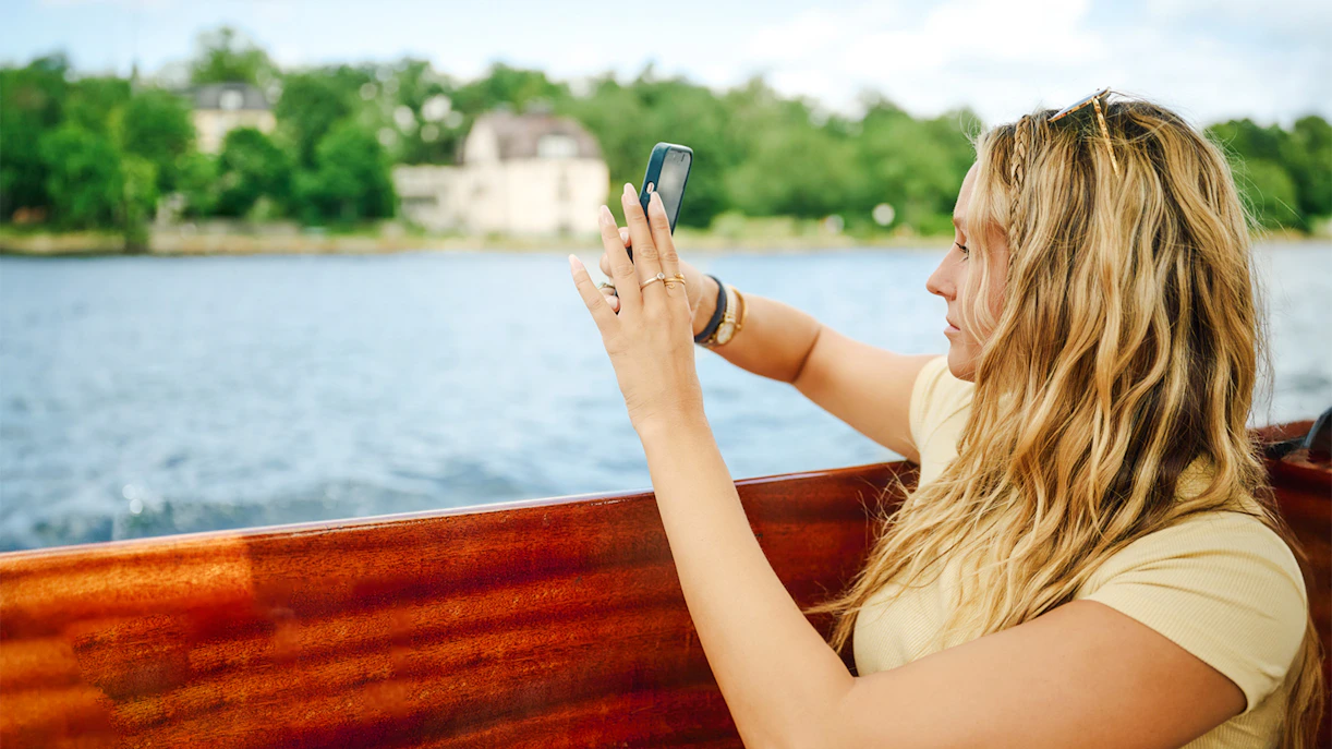Woman taking photo on wooden boat in Stockholm Archipelago.