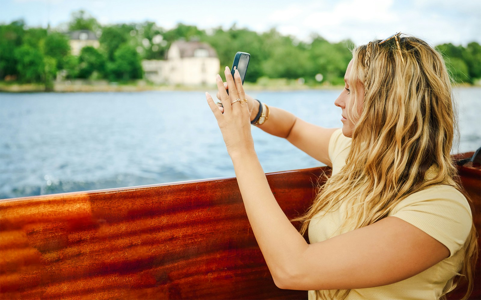 Woman taking photo on wooden boat in Stockholm Archipelago.