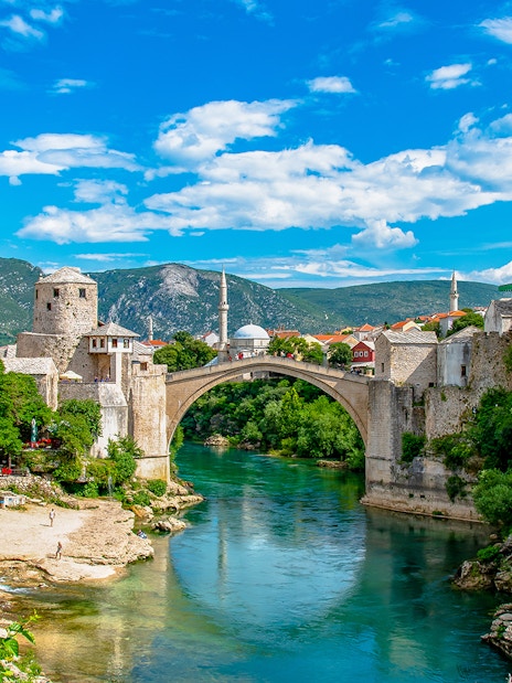 Stari Most bridge over Neretva River in Mostar, Bosnia and Herzegovina, with surrounding historic buildings.