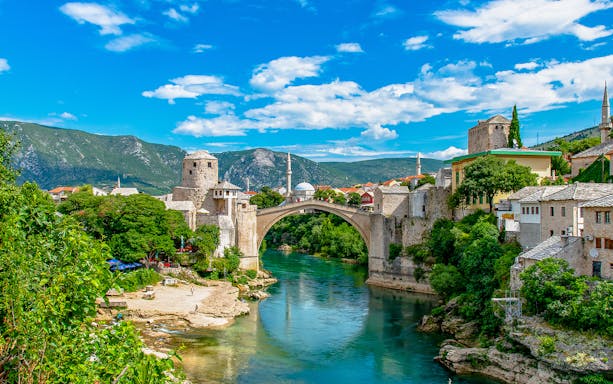 Stari Most bridge over Neretva River in Mostar, Bosnia and Herzegovina, with surrounding historic buildings.