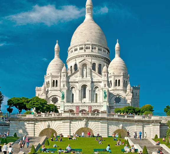 Sacre Coeur Cathedral on Montmartre hill with visitors on the lawn, Paris, France.