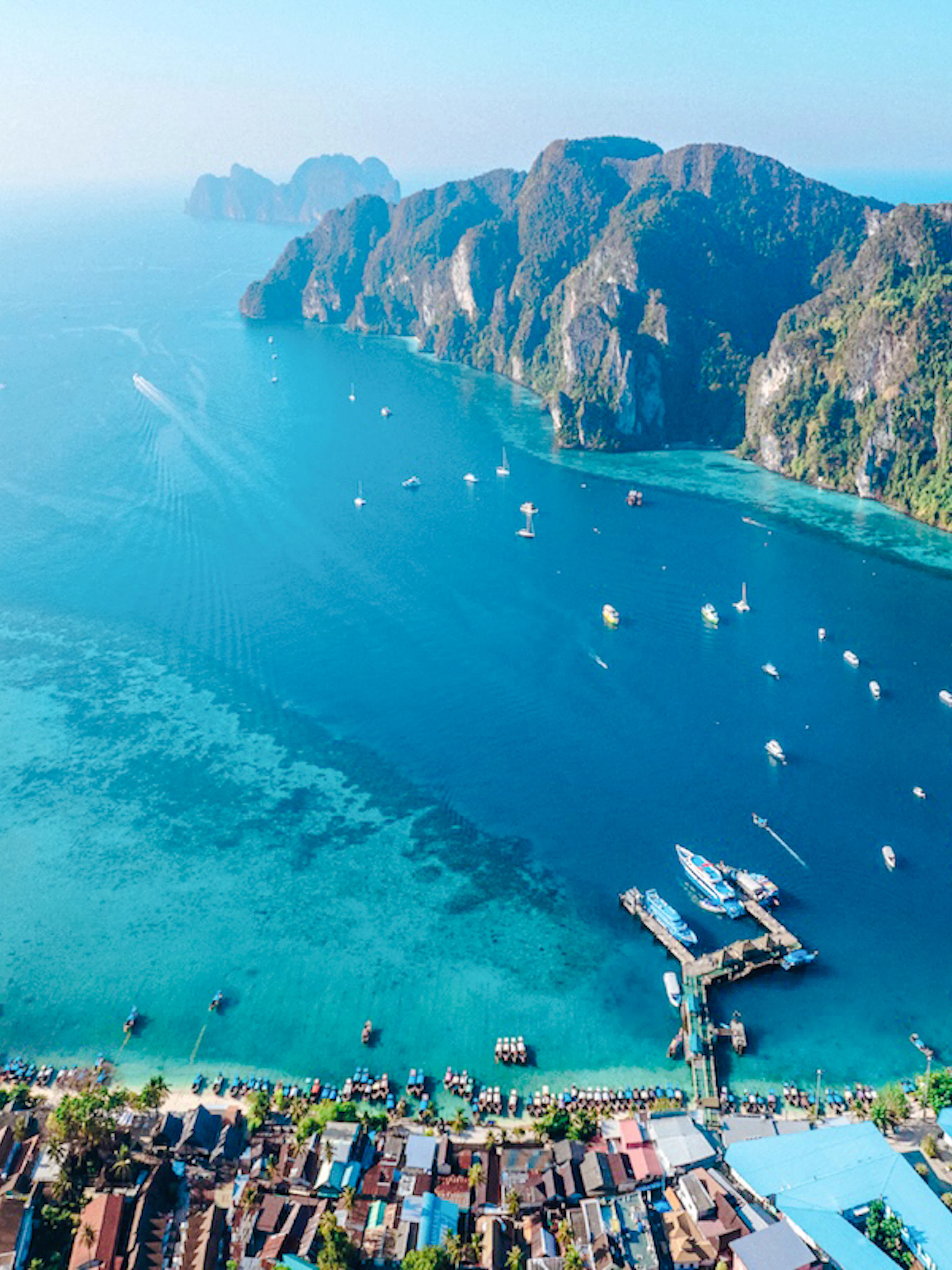 Aerial view of Phi Phi Island bay with boats and lush cliffs, part of Phuket to Phi Phi cruise.