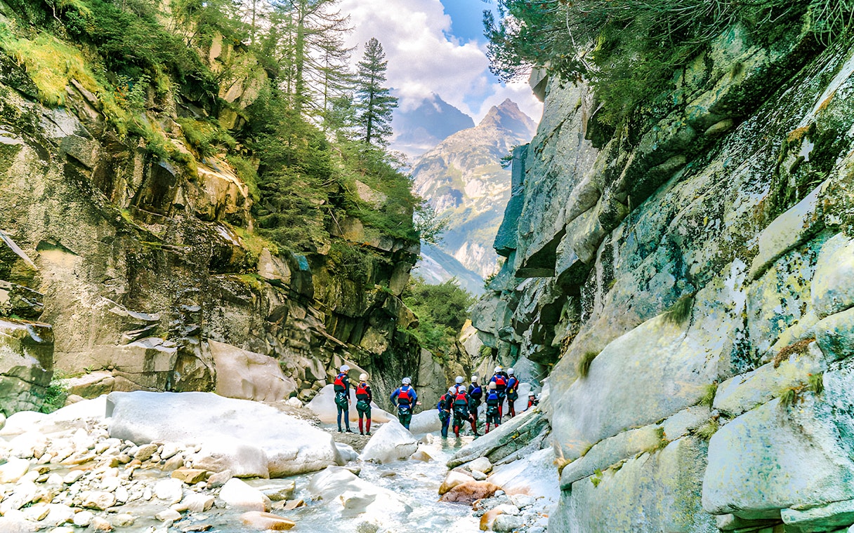 Canyoning group exploring Grimsel Canyon with rocky cliffs and lush greenery.