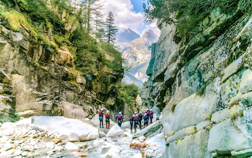 Canyoning group exploring Grimsel Canyon with rocky cliffs and lush greenery.