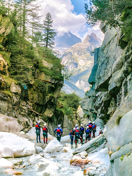 Canyoning group exploring Grimsel Canyon with rocky cliffs and lush greenery.