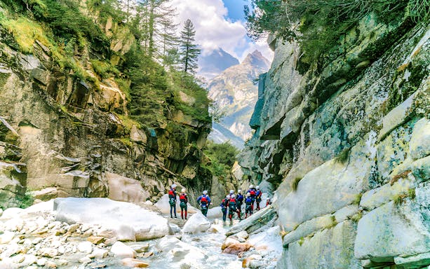 Canyoning group exploring Grimsel Canyon with rocky cliffs and lush greenery.