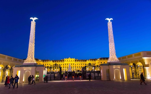 Schonbrunn Palace entrance lit up at night during the Christmas market in Vienna.