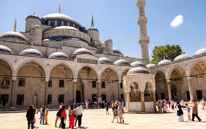Courtyard of the Blue Mosque in Istanbul with visitors exploring the historic architecture.