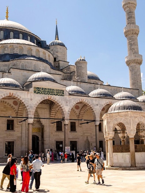 Courtyard of the Blue Mosque in Istanbul with visitors exploring the historic architecture.