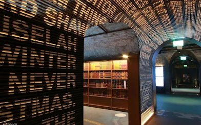 Dimly lit museum corridor with illuminated text wall and bookshelves, Epic Museum.