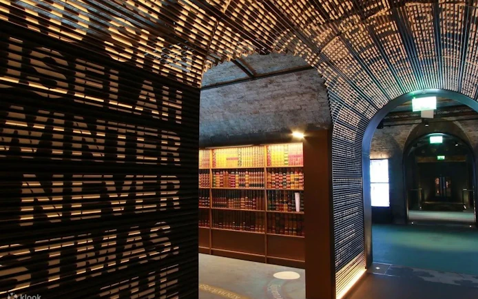 Dimly lit museum corridor with illuminated text wall and bookshelves, Epic Museum.