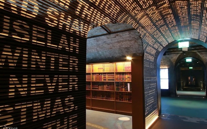 Dimly lit museum corridor with illuminated text wall and bookshelves, Epic Museum.