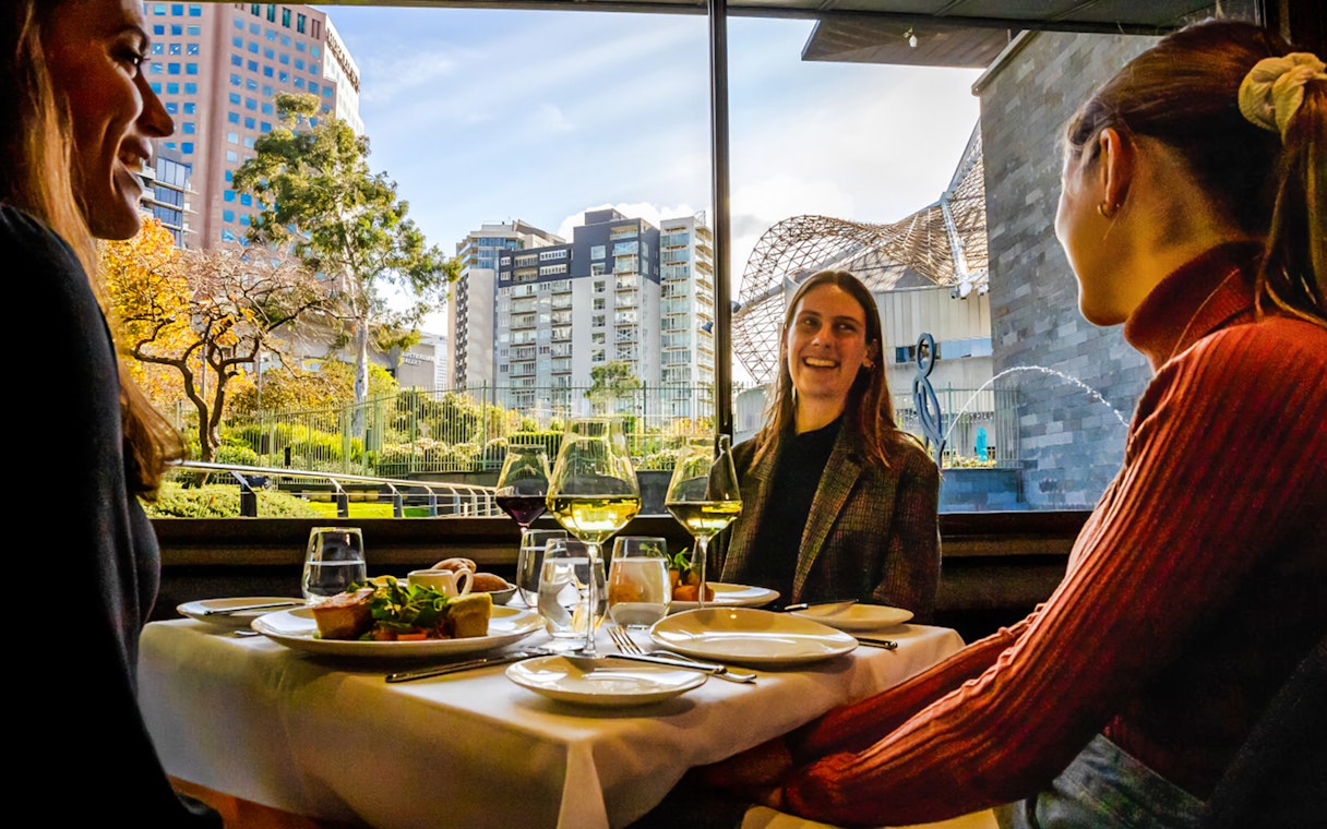 Tourists enjoying a three-course lunch at the National Gallery of Victoria with cityscape views.