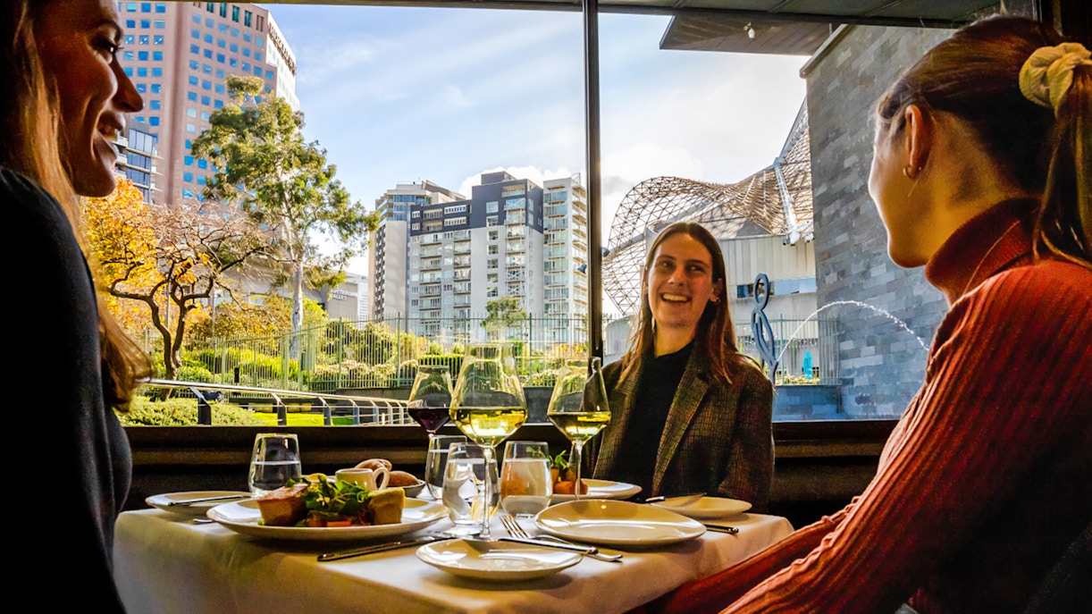 Tourists enjoying a three-course lunch at the National Gallery of Victoria with cityscape views.