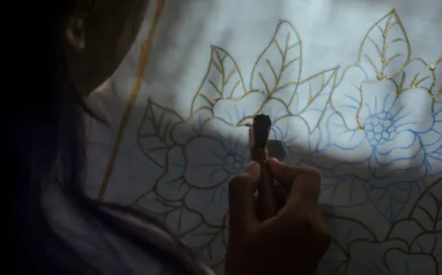 Batik painting in progress at a Yogyakarta workshop, featuring floral design outlines.