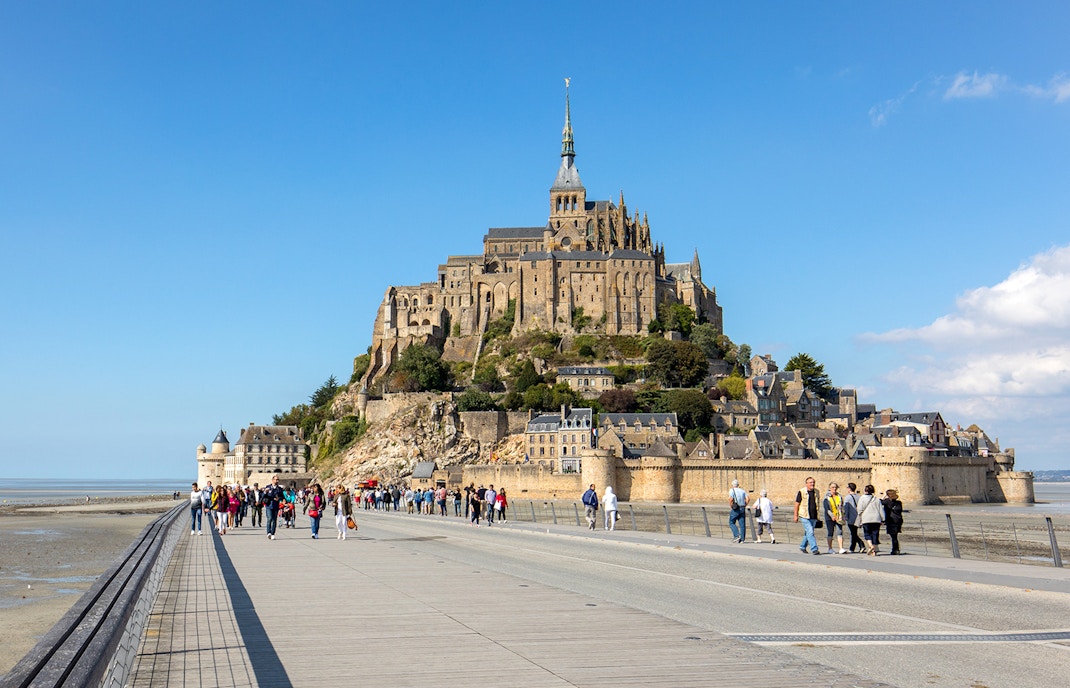 Mont Saint Michel Abbey in Normandy with tourists exploring the historic architecture.