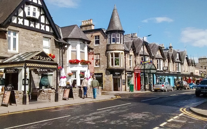 Street view of Pitlochry with traditional stone buildings and shops.