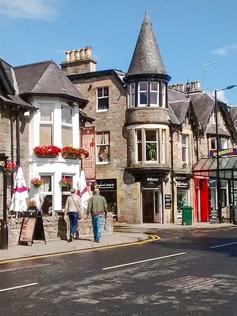 Street view of Pitlochry with traditional stone buildings and shops.
