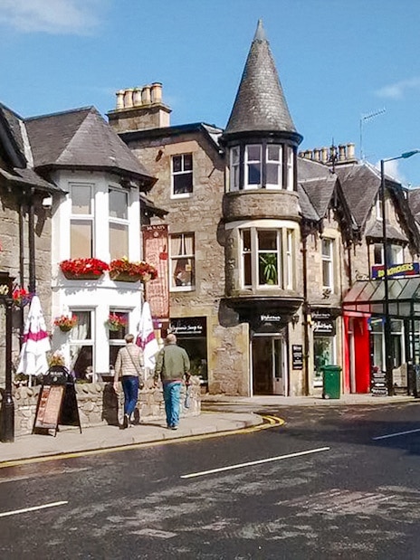 Street view of Pitlochry with traditional stone buildings and shops.