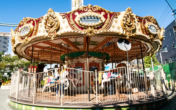 Ornate carousel with white horses and gold trim at outdoor amusement park.