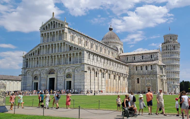 Guided tour group at Pisa's Field of Miracles with Leaning Tower in background.