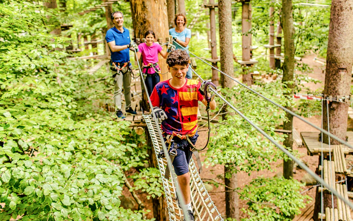 Family navigating a treetop rope course at Ropes Park Interlaken.