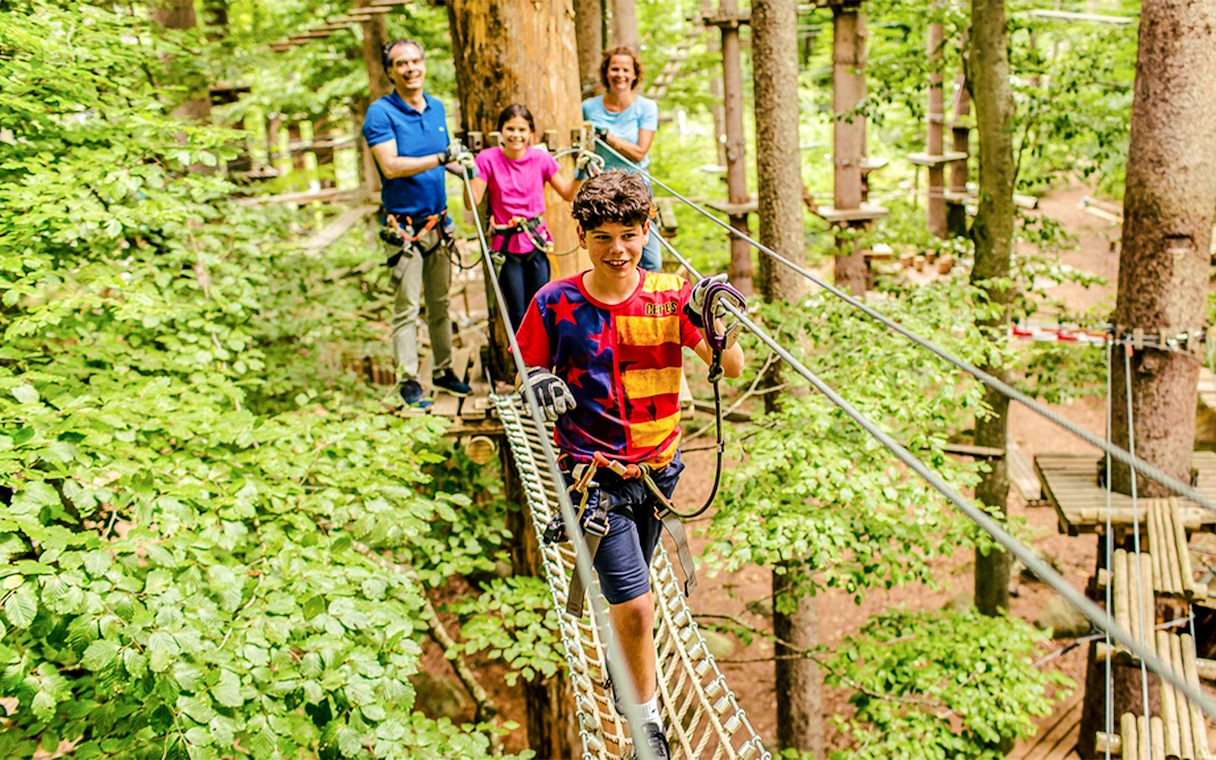 Family navigating a treetop rope course at Ropes Park Interlaken.